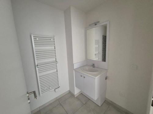 a white bathroom with a sink and a mirror at Appartement bella vista marseillan in Marseillan