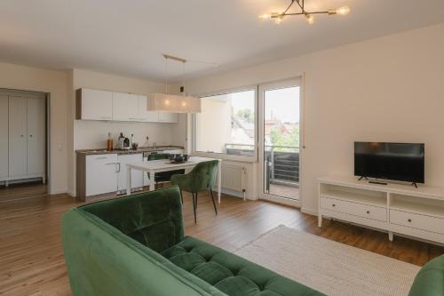 a living room with a green couch and a kitchen at Exklusiv & Zentral: 1-Zi. Apartment mit Balkon Stellplatz in Bayreuth