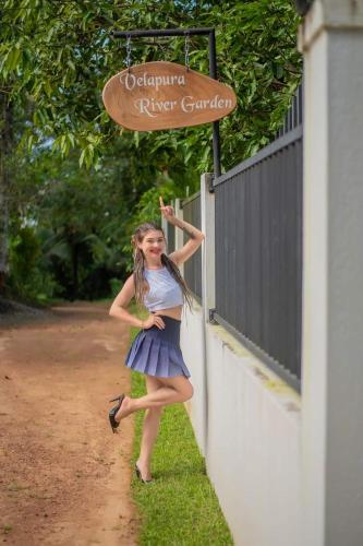 a young girl in a dress leaning against a fence at Velapura River Garden in Kalutara