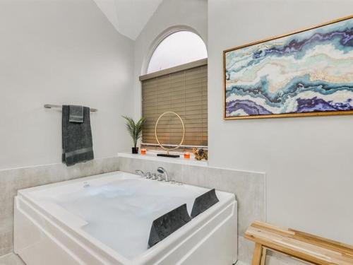 a large white tub in a bathroom with a painting at Captivating 6BR 3BA Holiday Home with Pool & Fire Pit in Mesquite