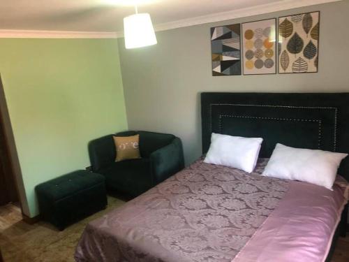 een slaapkamer met een bed en een stoel bij Bridges incorporated limited in Entebbe