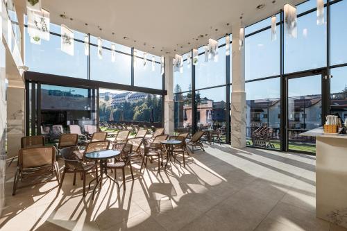 a patio with tables and chairs and large windows at Tavel Hotel & SPA in Bukovel