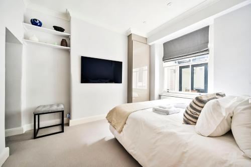 a white bedroom with a bed and a flat screen tv at New chic and luxury apartment in London