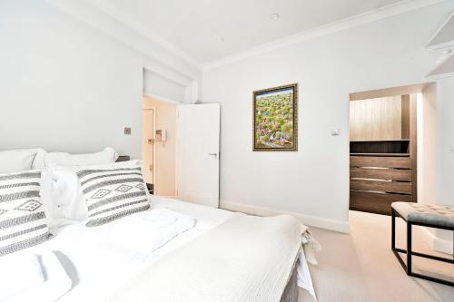 a white bedroom with a bed and a chair at New chic and luxury apartment in London