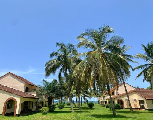 a group of palm trees in front of a house at Kololi Beach Resort in Kololi