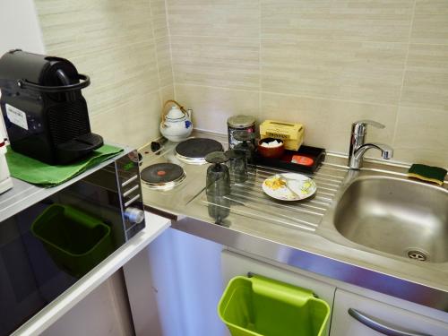 une petite cuisine avec un évier et un micro-ondes dans l'établissement Auberge du Cronquelet, à Saint-Aubin