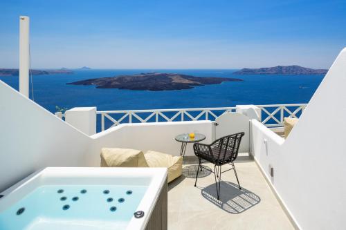 a balcony with a hot tub and a table and chairs at Elia Caldera Suites in Fira