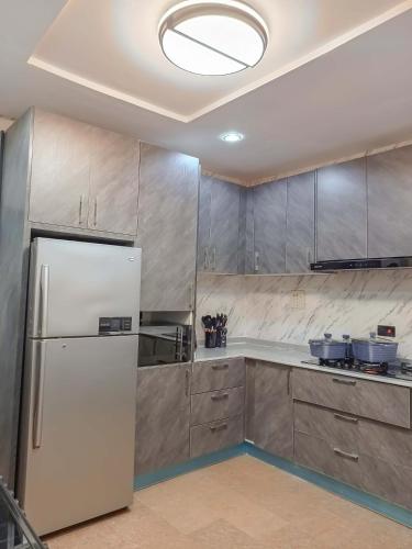 a kitchen with a white refrigerator and wooden cabinets at Kolebus Luxury Apartments in Abuja