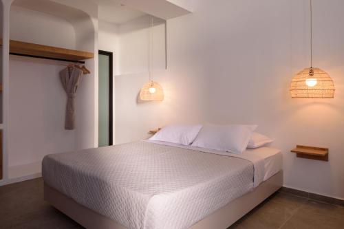 a bedroom with a white bed and two pendant lights at Elia Caldera Suites in Fira