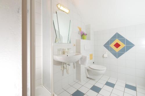 a white bathroom with a sink and a toilet at Gasthof Kraxner in Hatzendorf