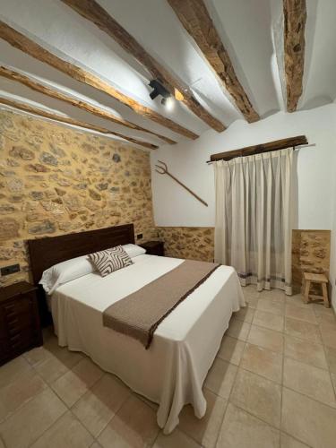 a bedroom with a large bed and a stone wall at Casas rurales La Fuente I in Villora