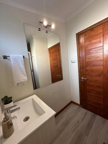 Un baño con lavabo y un espejo grande. en Roqueríos Logde, Tinaja incluida, Antuco, en Antuco