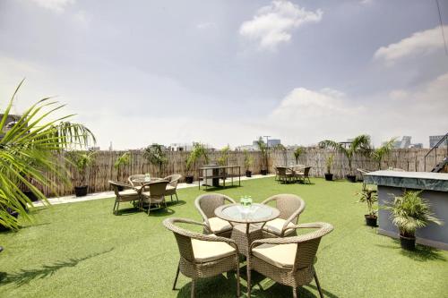 a patio with tables and chairs on the grass at Saltstayz Premier - Cyber Hub in Gurgaon