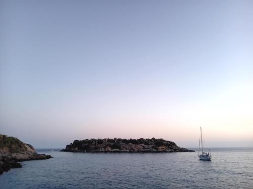 a sailboat on a small island in the water at Olympia Koumanakou Rooms Δωμάτια Ολυμπίας Κουμανάκου in Kardamili