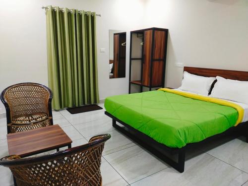 a bedroom with a bed with a green blanket at Bamboo Suite at Merlys Fruit Garden in Kotamangalam