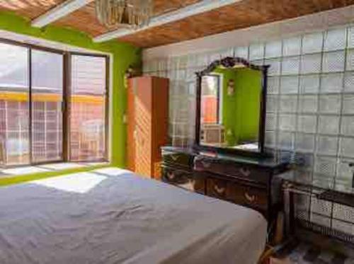 a bedroom with a bed and a dresser and a mirror at Casa Cabo, Bungalow & Surf in Cabo San Lucas