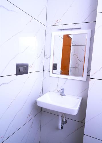 a white bathroom with a sink and a mirror at Chittinappilly Cottage in Angamaly