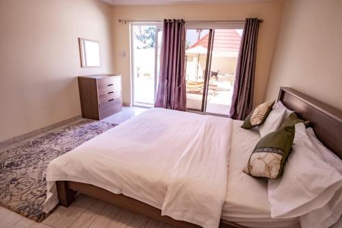 a bedroom with a large white bed and a window at Kololi Beach Resort in Kololi
