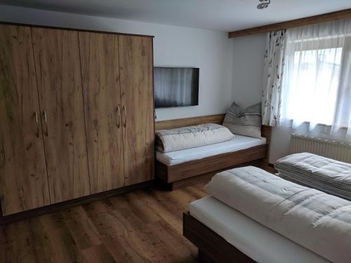 レオガングにあるFerienwohnung Rainer Kunterbuntのベッドルーム1室(ベッド2台、大きな木製キャビネット付)