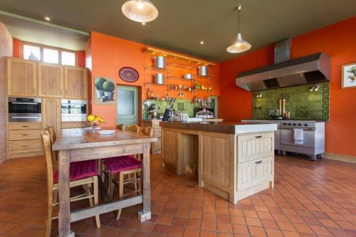 une grande cuisine avec des murs orange et un grand îlot dans l'établissement Location maison & gîte Normandie, à Tamerville