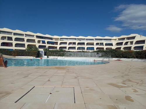 un grand bâtiment avec une piscine devant dans l'établissement Appartement climatisé avec piscine proche mer, au Grau-du-Roi