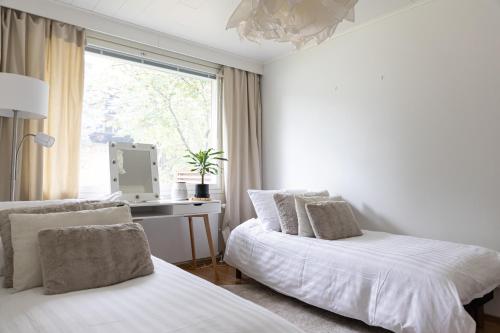 two beds in a room with a desk and a window at Aurora Row House in Rovaniemi