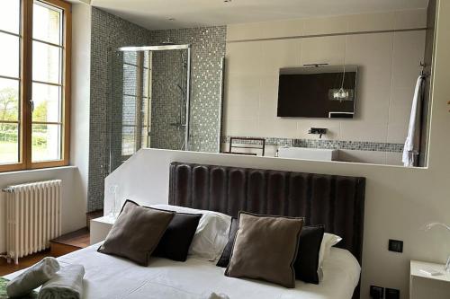 une chambre avec un lit avec des draps blancs et des oreillers dans l'établissement Location maison & gîte Normandie, à Tamerville