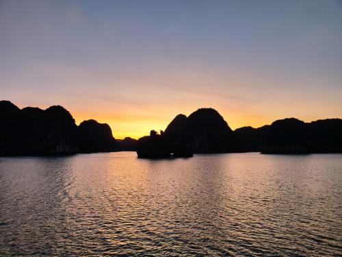 a sunset on the water with mountains in the background at Catba Cannon Fort Hotel & Spa in Cat Ba