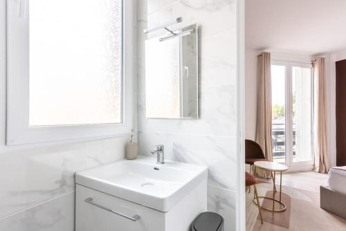 une salle de bain blanche avec un lavabo et un miroir dans l'établissement Studio lumineux Paris Est -II, à Paris