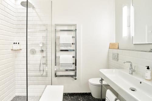 a white bathroom with a shower and a sink at Normandy Le Chantier in Paris