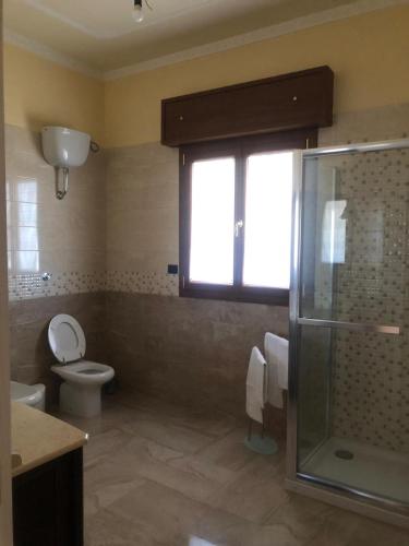 a bathroom with a shower and a toilet and a window at Tramonti salentini in San Marzano di San Giuseppe