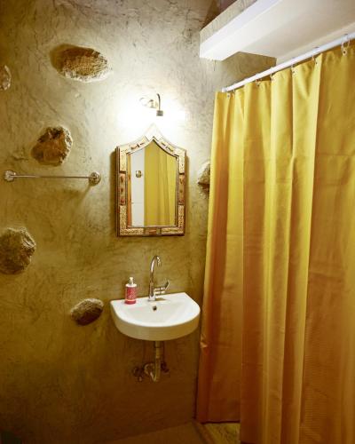 a bathroom with a sink and a yellow shower curtain at Guest house Dimitra in Sitia