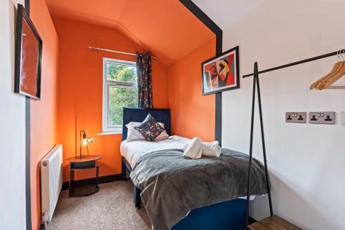 a bedroom with an orange room with a bed and a window at 4 Bedroom, 2 Bath in NewCastle Town Centre in Newcastle under Lyme