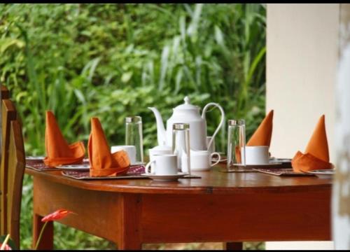 een tafel met kopjes en schotels erop bij Sinharaja Hostel 114 in Deniyaya
