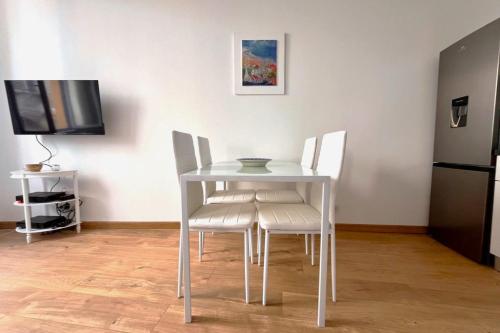 une table blanche avec des chaises blanches et une télévision dans l'établissement 1BR in Historic Center of Grasse - BENAKEY, à Grasse
