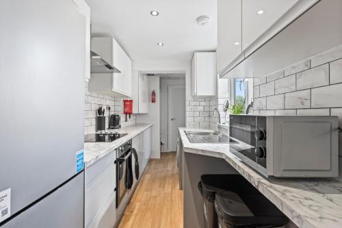 a white kitchen with a sink and a microwave at 4 Bedroom, 2 Bath in NewCastle Town Centre in Newcastle under Lyme