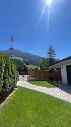 a yard with a house and a fence and grass at Hotel-Garni Austria in Westendorf