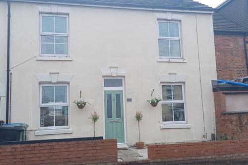 a white house with a green door and windows at Rugby town centre house close to train station, rugby school and benn hall in Rugby