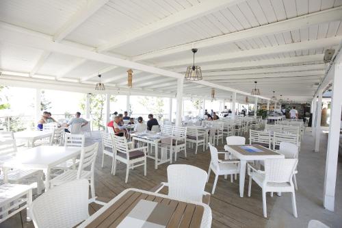 a white restaurant with white tables and white chairs at Hotel Vila Barbaut in Karpen
