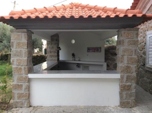 an outdoor kitchen in a stone building with a roof at Quinta da Capela in Gouveia