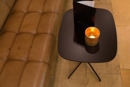 a candle sitting on a stool next to a leather chair at Hotel am See in Hard