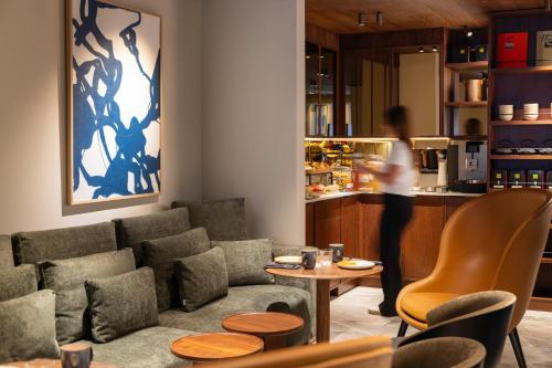 a woman standing in a living room with a couch and a table at Hôtel Gabbie in Paris
