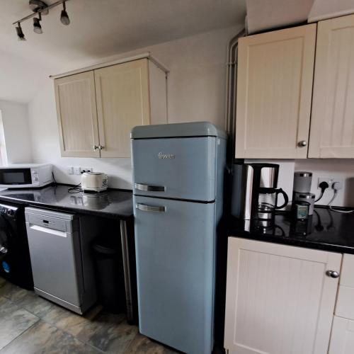 a small kitchen with a refrigerator and cabinets at Huge 4 bed in the heart of Kettering in Kettering