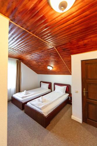 two beds in a room with a wooden ceiling at Resort EuroPark Fundata in Fundata