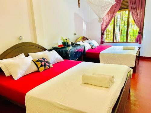 a bedroom with three beds with red and white sheets at The Grandiose Safari in Udawalawe