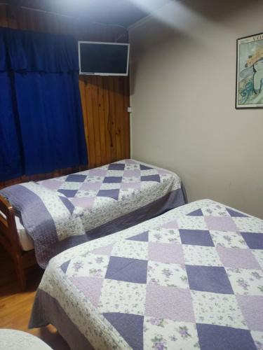 two beds in a room with a quilt at Hostal Saint Michell. El Quisco in El Quisco