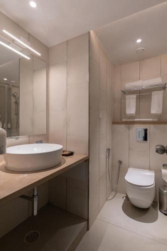 a bathroom with a tub and a toilet and a sink at Spektrum Hotel - Bengaluru Airport in Bangalore