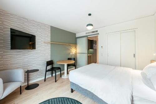 a bedroom with a white bed and a tv on a brick wall at Aparthotel Adagio Muenchen City in Munich