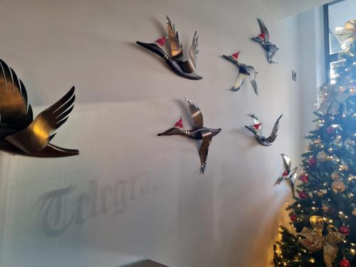a group of birds on a wall next to a christmas tree at Telegraph Hotel - Coventry in Coventry
