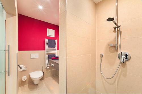 a bathroom with a toilet and a red wall at Hotel Raphael im Allgäu in Kempten